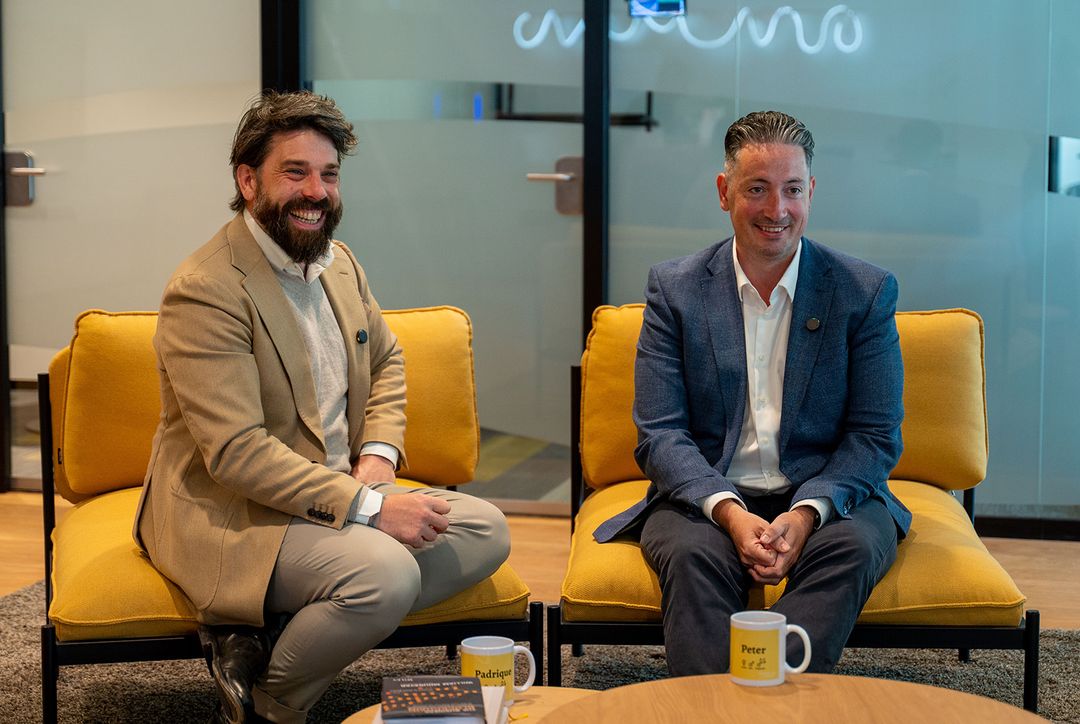 Twee JVT-specialisten op gele stoelen op kantoor